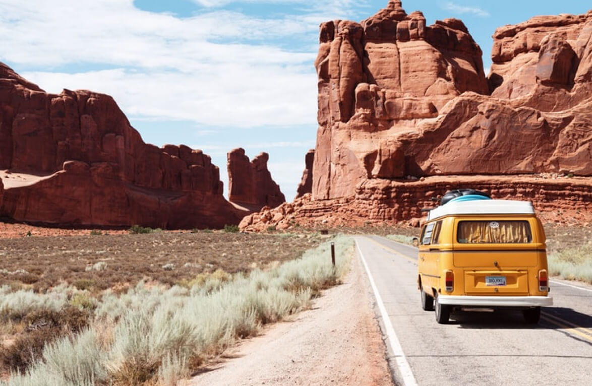 A mini van crossing a road between canyons