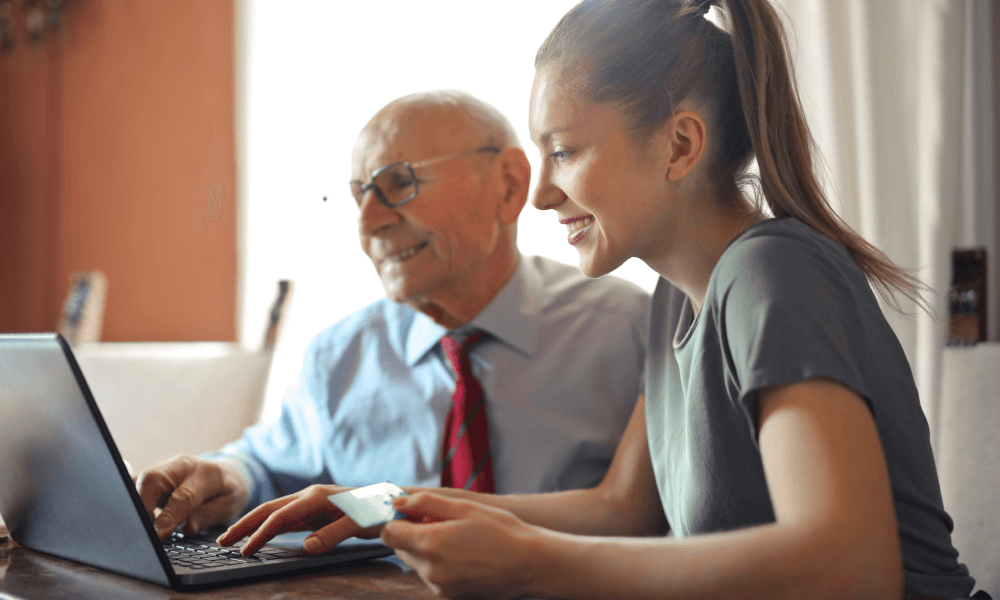 Young woman helping senior man make an online donation